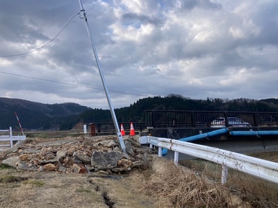 地震により破損した水道管と傾いた街灯の写真